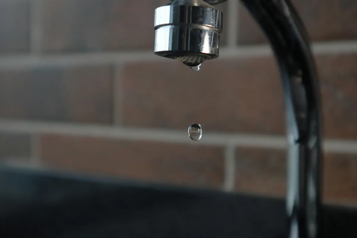 Llave de agua con una gota a punto de caer